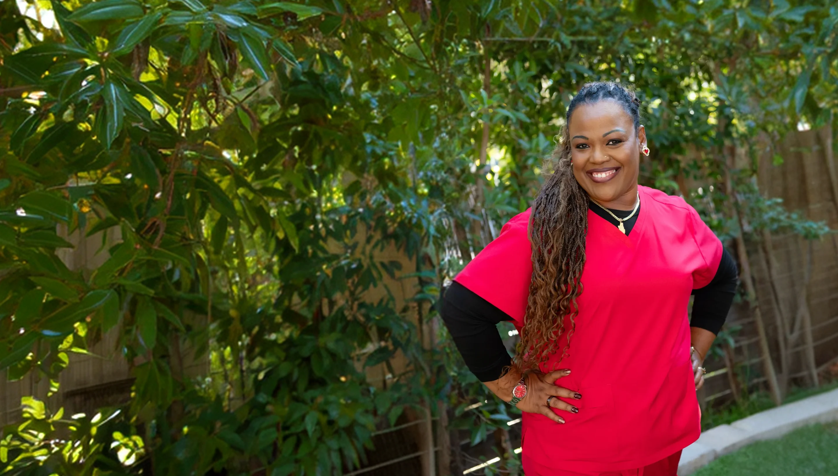 Nurse in scrubs smiling outside a home