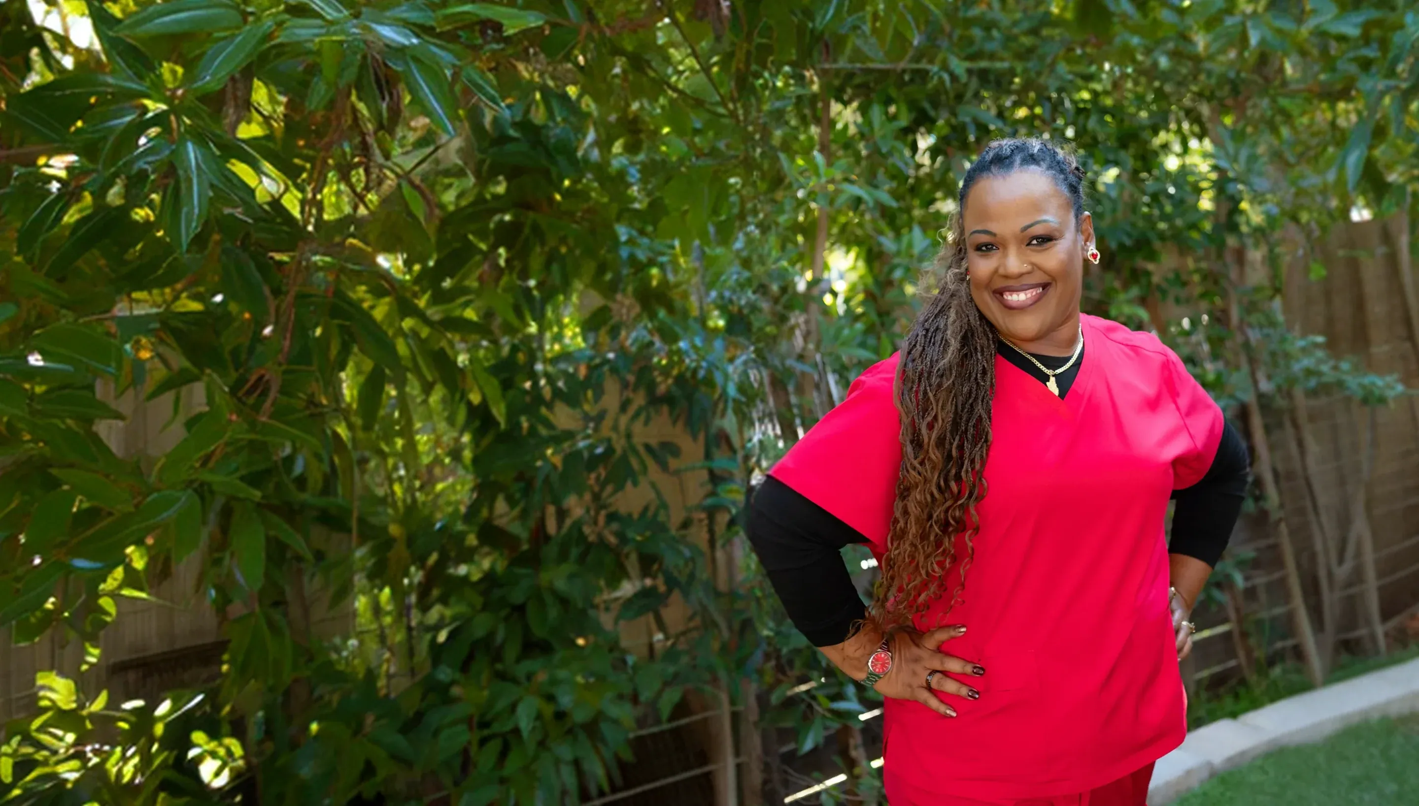 Nurse in scrubs smiling outside a home