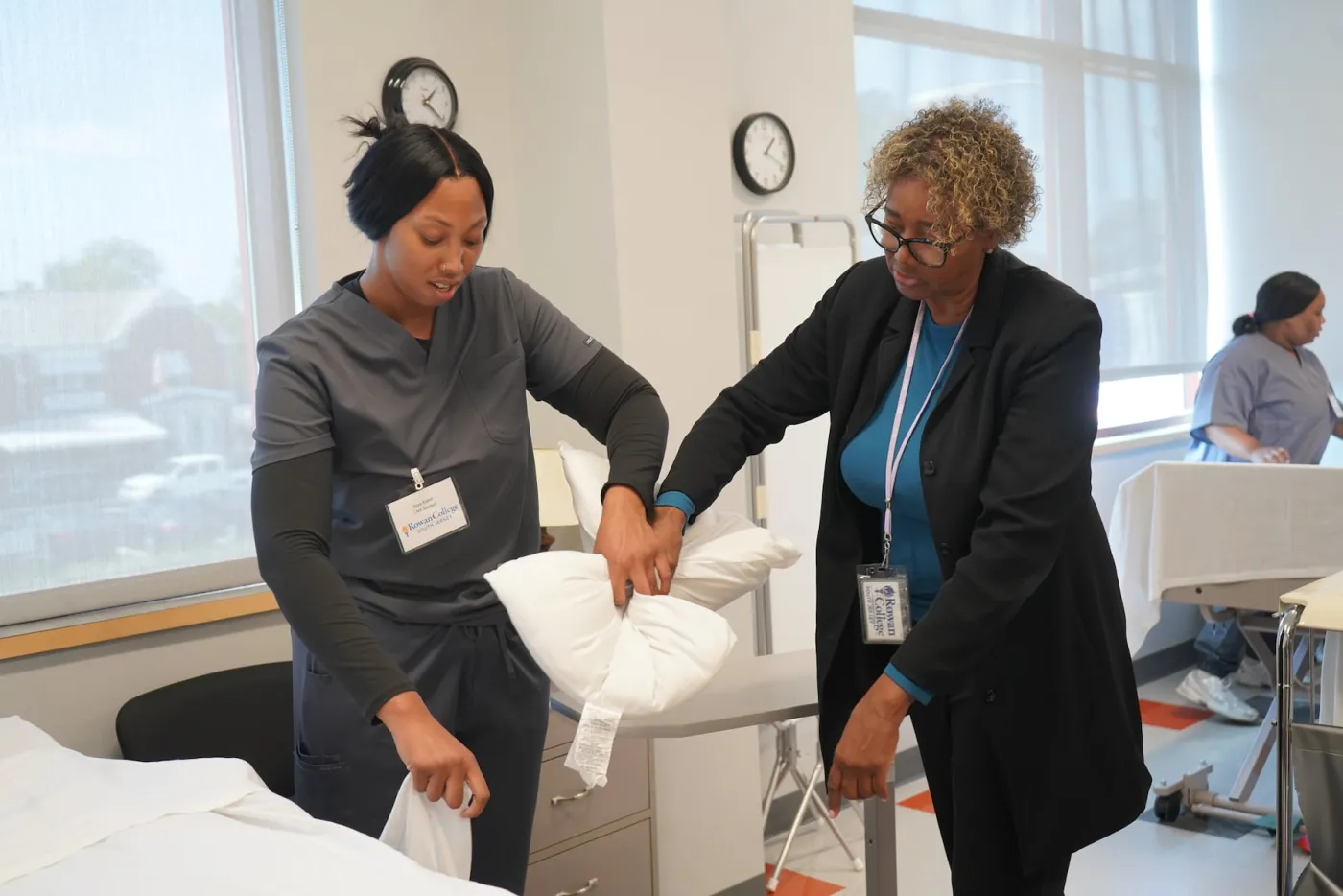 A certified nursing assistant trainee learns how to make a bed alongside her instructor at Rowan College of South Jersey.